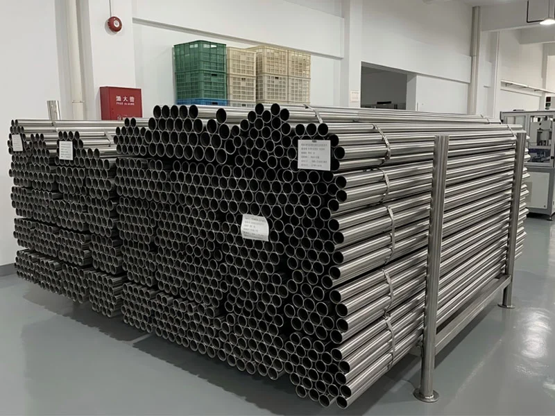 A neatly organized stack of stainless steel pipes in an industrial storage area.