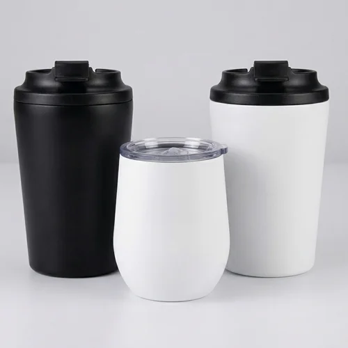 Set of black and white stainless steel tumblers with flip lids and a stemless cup for hot or cold beverages.